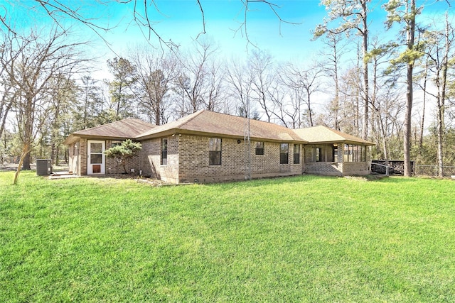 back of house with brick siding, central AC unit, a yard, and fence