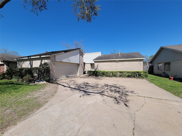 exterior space featuring brick siding, a lawn, concrete driveway, and a garage