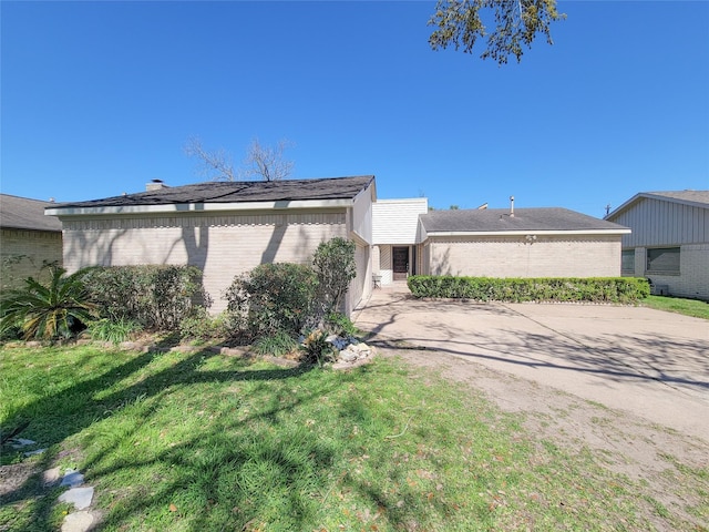 view of side of property featuring concrete driveway, a lawn, and brick siding