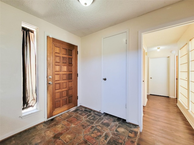 entrance foyer with baseboards and a textured ceiling