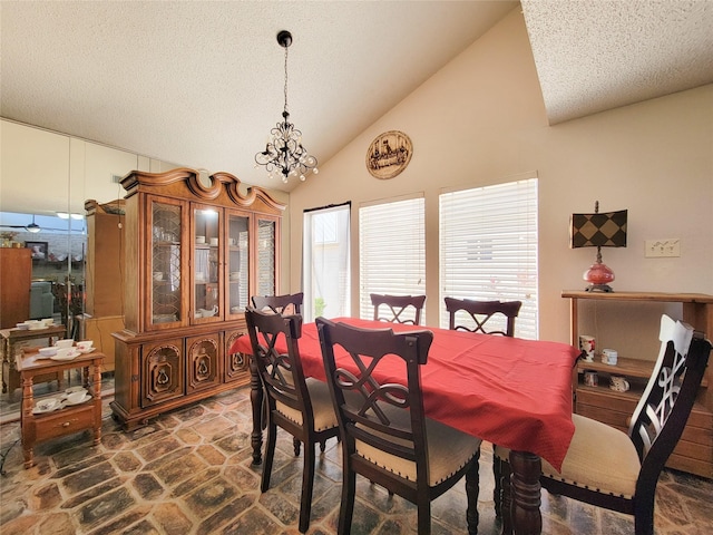 dining room featuring lofted ceiling, stone finish floor, a notable chandelier, and a textured ceiling