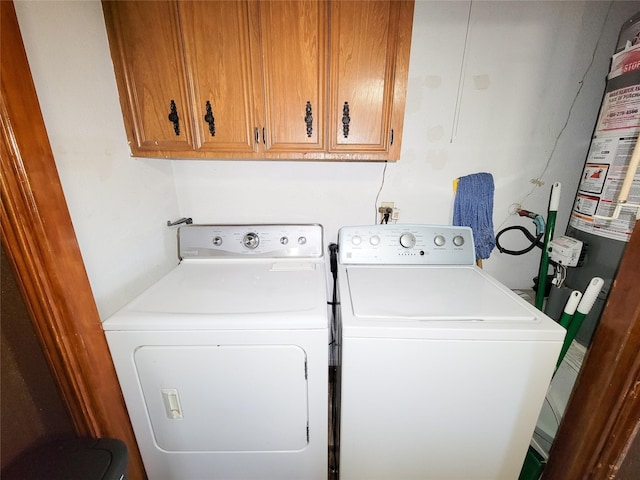 laundry area with washing machine and clothes dryer, cabinet space, and gas water heater