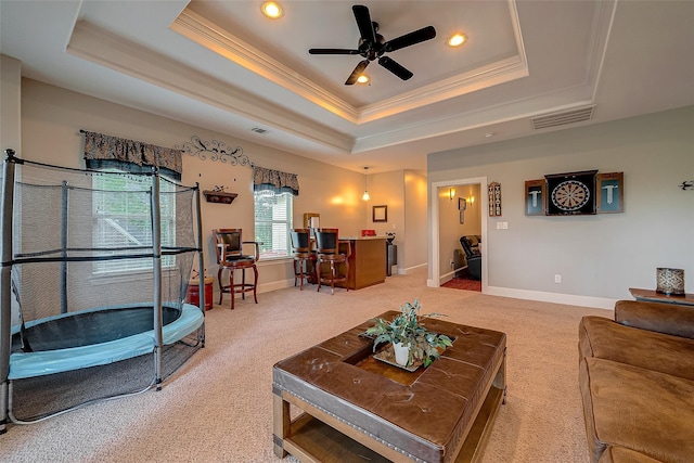 living area featuring baseboards, visible vents, ornamental molding, light carpet, and a raised ceiling