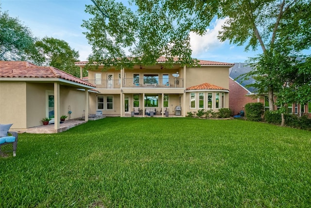 rear view of house featuring stucco siding, a balcony, a patio area, and a tiled roof