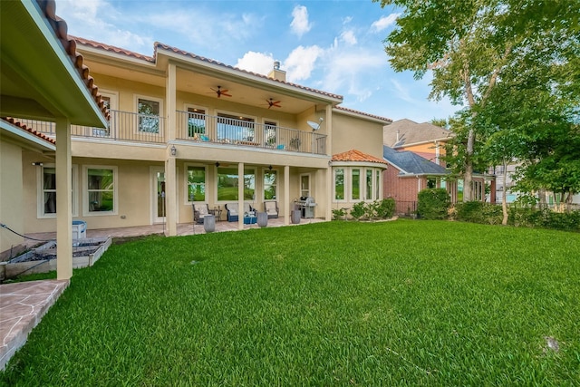 rear view of house with a balcony, a ceiling fan, and stucco siding