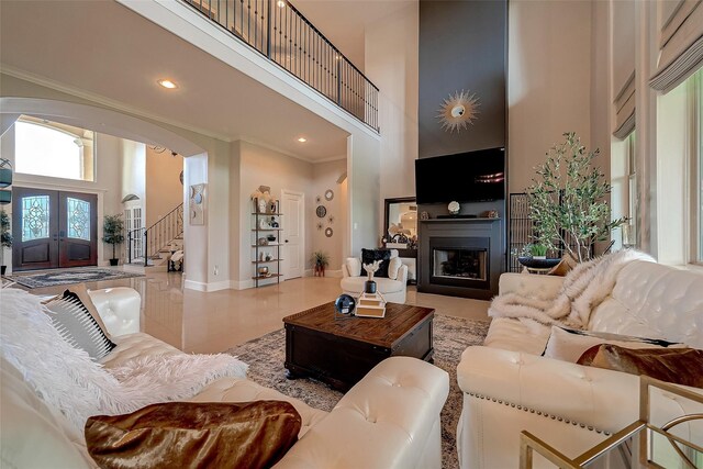 living room with a high ceiling, arched walkways, and ornamental molding