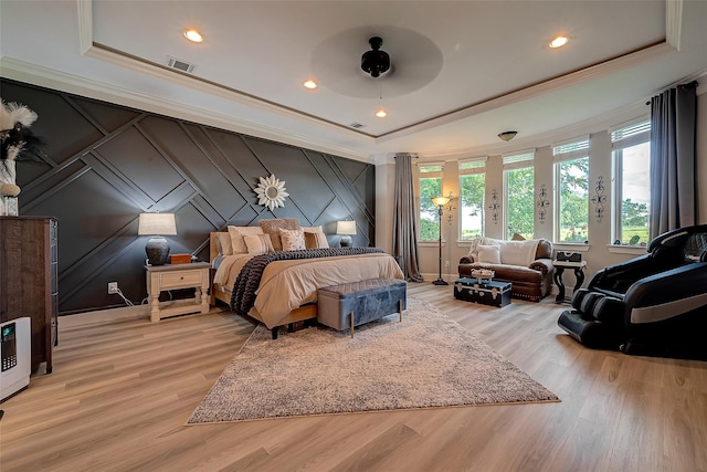 bedroom with a decorative wall, visible vents, crown molding, and a raised ceiling