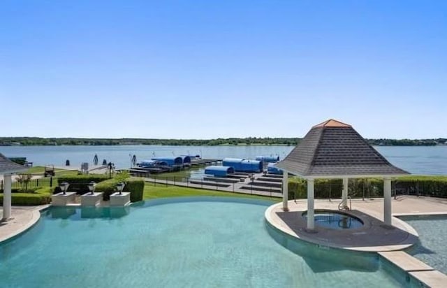 pool featuring a gazebo, fence, an in ground hot tub, and a water view