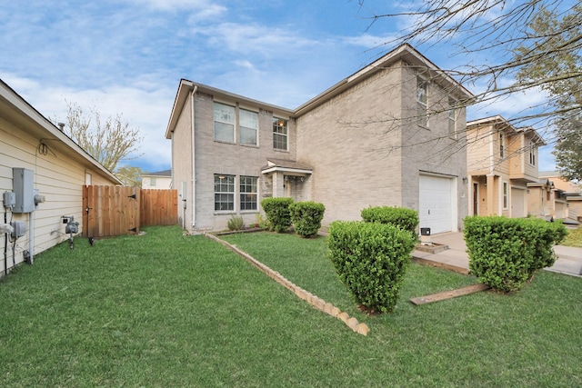 back of property with a yard, brick siding, an attached garage, and fence