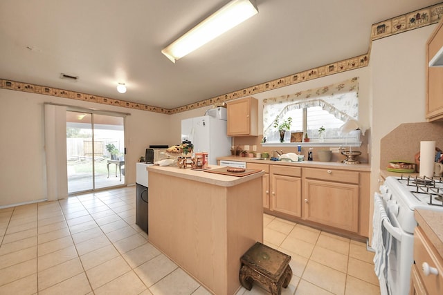 kitchen featuring white appliances, a center island, light brown cabinetry, and light countertops