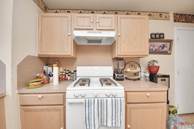 kitchen with white range with gas stovetop, under cabinet range hood, and light brown cabinetry