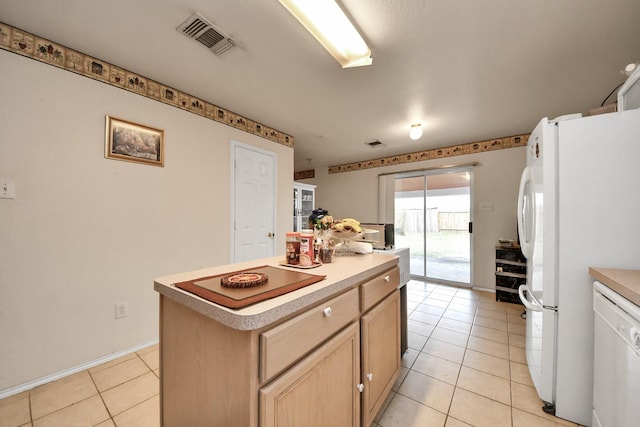 kitchen with white appliances, light tile patterned floors, visible vents, a kitchen island, and light brown cabinetry