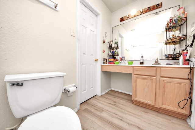 bathroom with toilet, vanity, baseboards, and wood finished floors