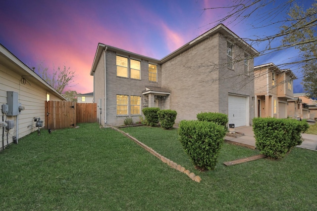 back of house with a garage, a lawn, brick siding, and fence