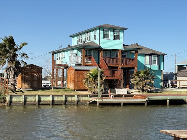 back of house with a storage unit, an outdoor structure, and a water view