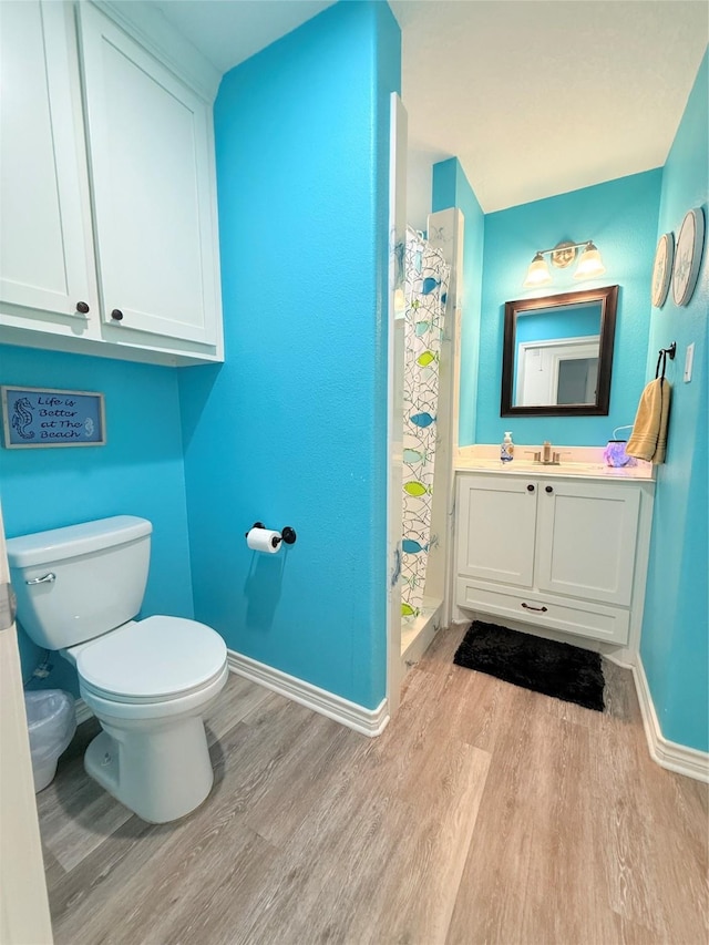 full bathroom with toilet, vanity, baseboards, and wood finished floors