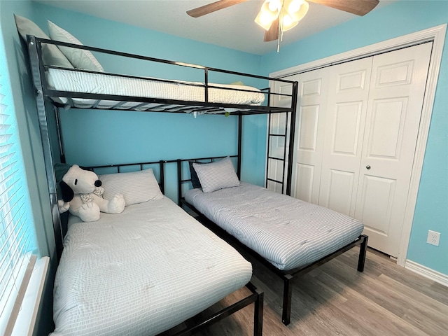 bedroom featuring a ceiling fan, wood finished floors, a closet, and baseboards