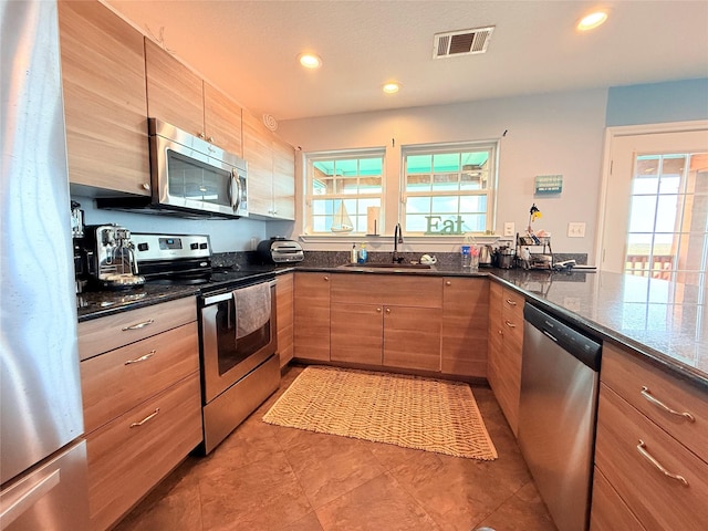 kitchen featuring visible vents, a sink, dark stone countertops, recessed lighting, and appliances with stainless steel finishes