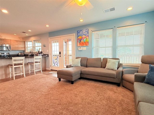 carpeted living room with a sink, french doors, visible vents, and recessed lighting