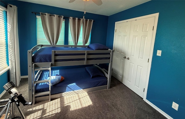 carpeted bedroom featuring baseboards, multiple windows, a closet, and a ceiling fan