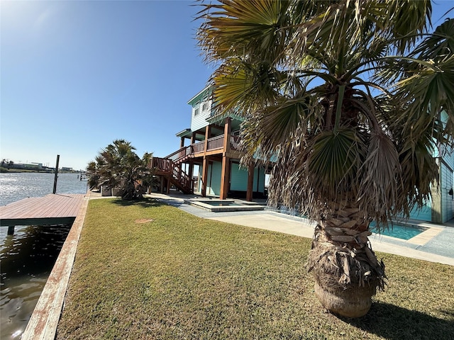 view of yard with stairway, a hot tub, a boat dock, and a water view