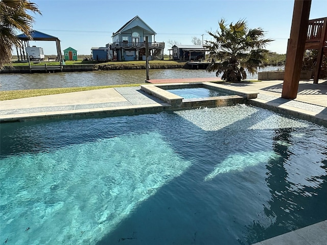 view of swimming pool with a water view, a pool with connected hot tub, and a patio area