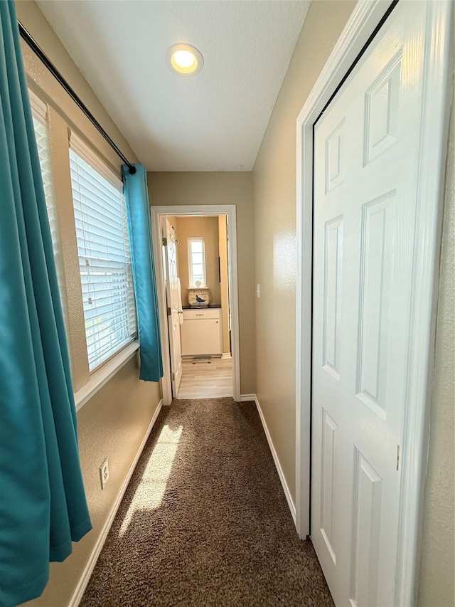 corridor featuring baseboards and carpet floors