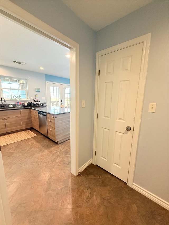 kitchen featuring dark countertops, visible vents, baseboards, modern cabinets, and stainless steel dishwasher