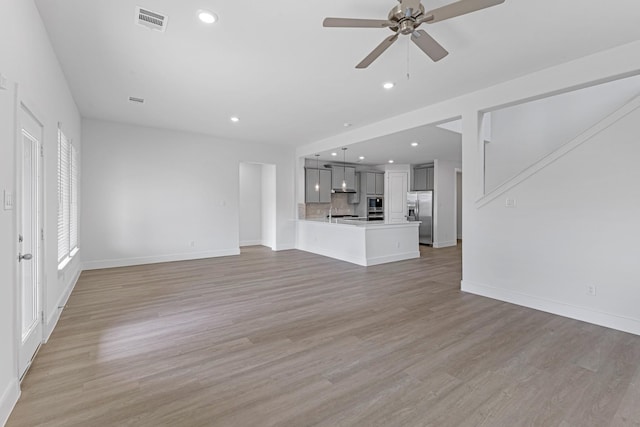 unfurnished living room featuring light wood-type flooring, visible vents, a ceiling fan, recessed lighting, and baseboards