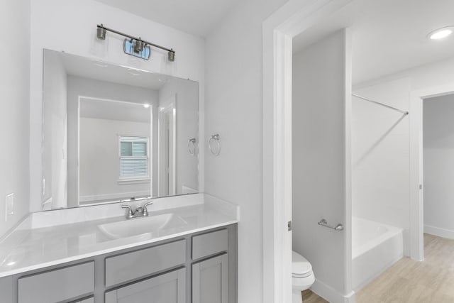 full bathroom with baseboards, toilet, shower / tub combination, wood finished floors, and vanity