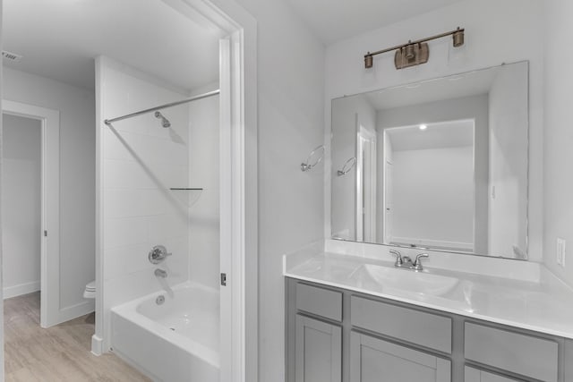 full bathroom with toilet, wood finished floors, vanity, baseboards, and shower / bathtub combination