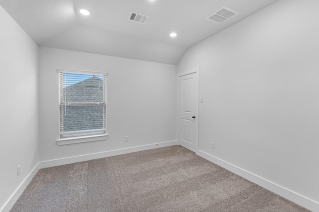 empty room featuring visible vents, baseboards, carpet, and lofted ceiling