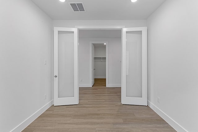 interior space featuring visible vents, a walk in closet, a closet, light wood-style floors, and baseboards