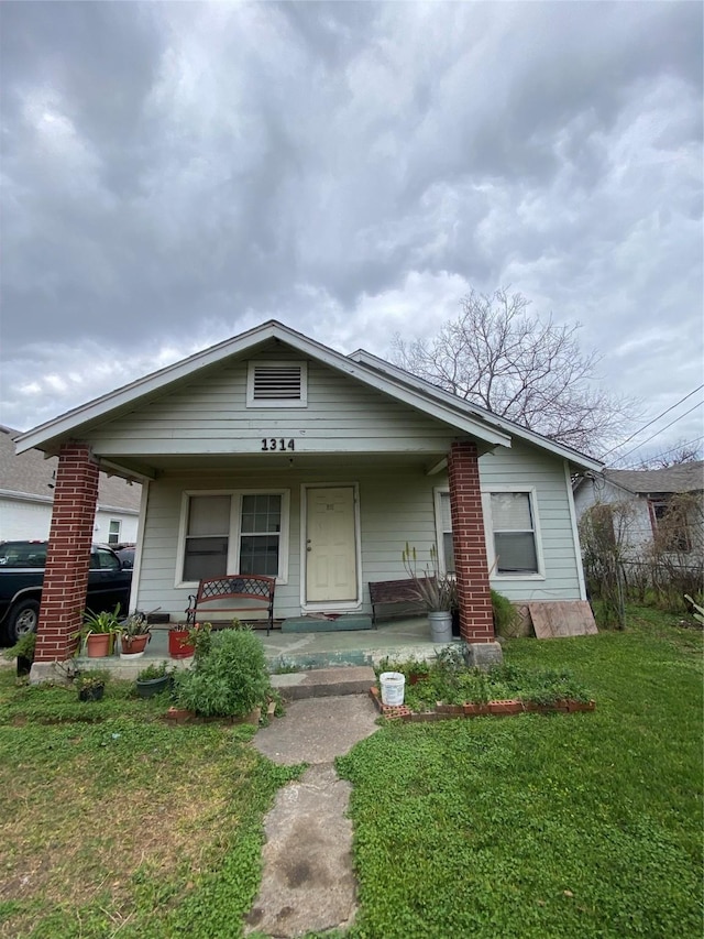 bungalow-style house with a front lawn and covered porch