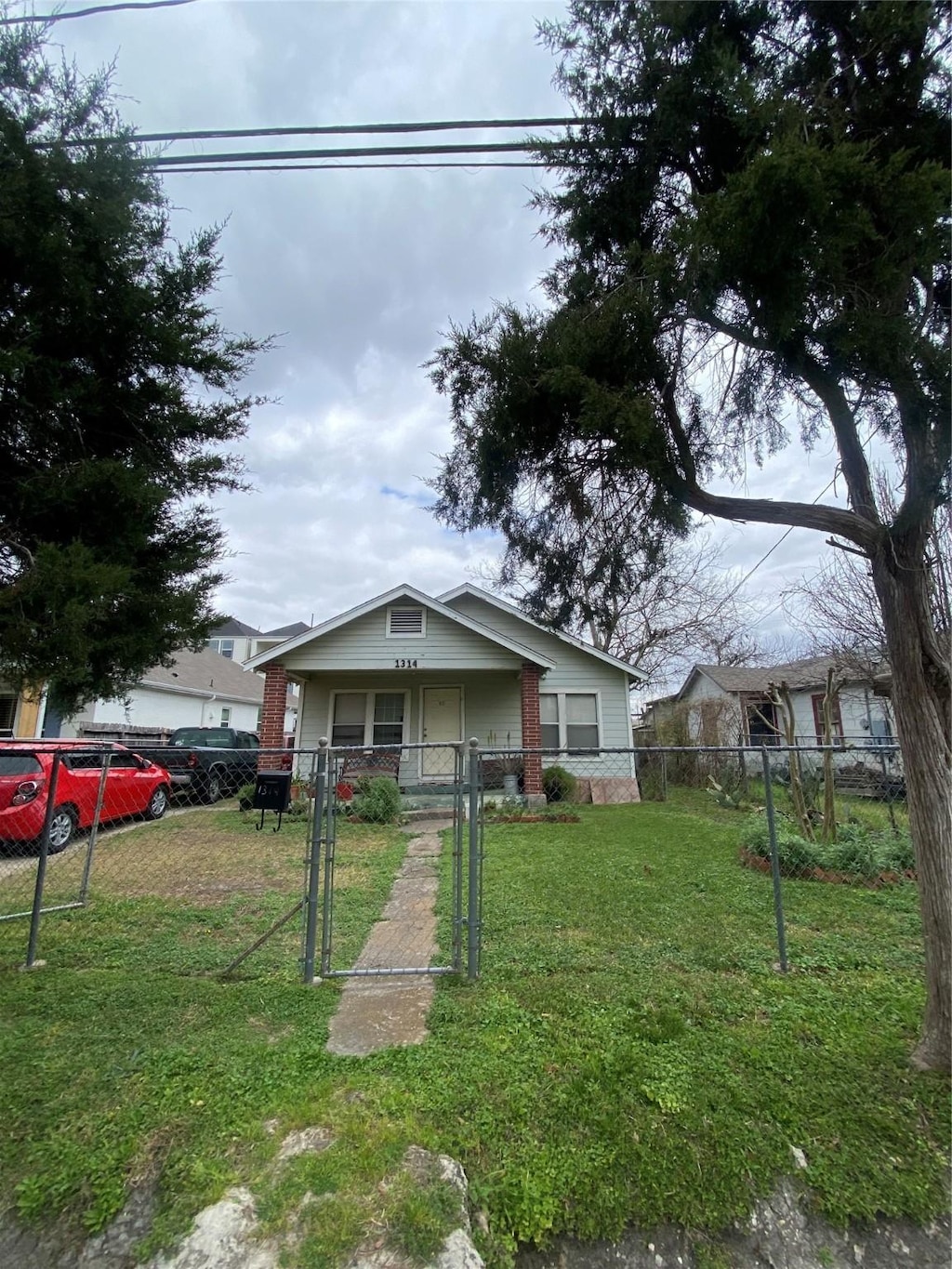 bungalow-style home featuring a front lawn, a gate, covered porch, and a fenced front yard