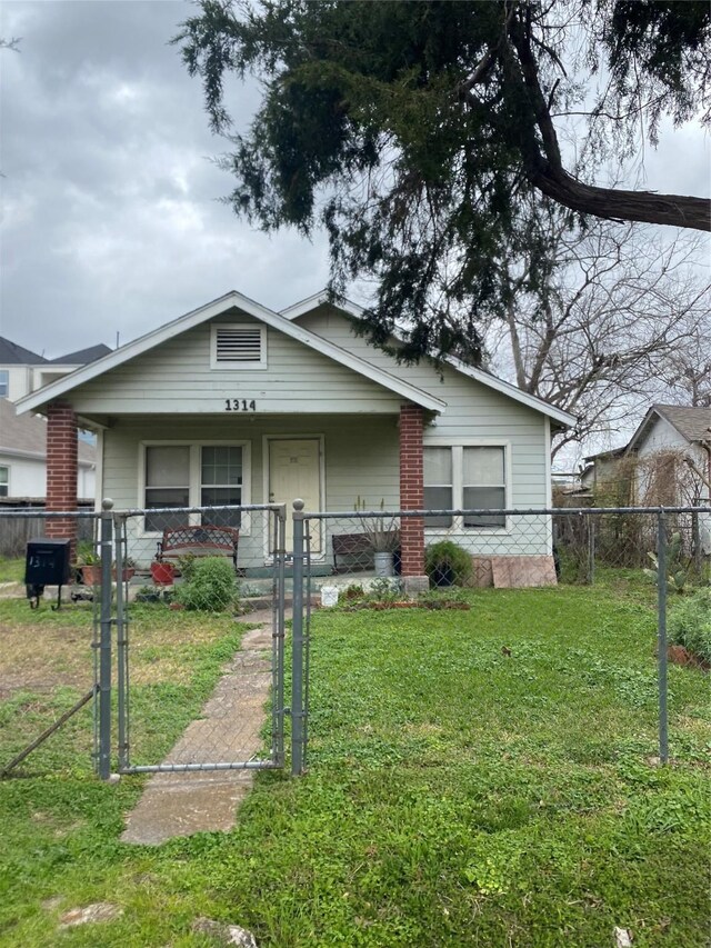 bungalow-style house featuring a front lawn, a fenced front yard, covered porch, and a gate