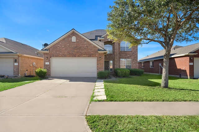 traditional-style home featuring brick siding, solar panels, a front lawn, driveway, and an attached garage