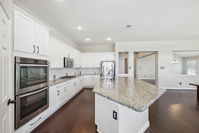 kitchen with visible vents, white cabinetry, stainless steel appliances, and a sink