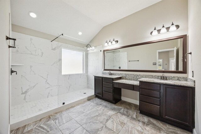 bathroom featuring double vanity, a marble finish shower, lofted ceiling, and a sink