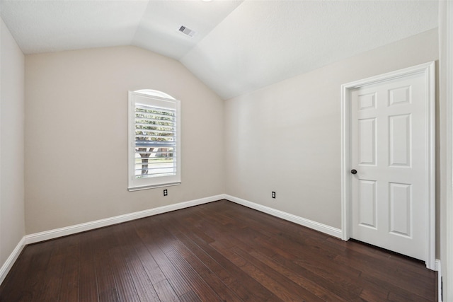 unfurnished room with vaulted ceiling, dark wood-style floors, visible vents, and baseboards