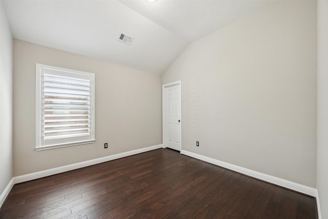 unfurnished room featuring dark wood-style floors, visible vents, baseboards, and vaulted ceiling