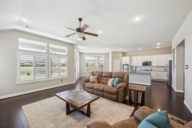 living area with recessed lighting, visible vents, baseboards, and dark wood finished floors