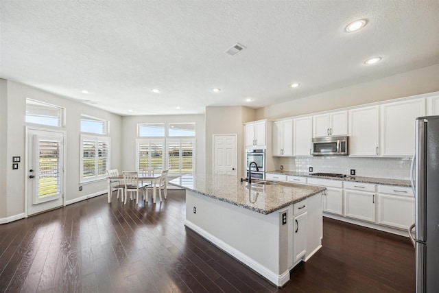 kitchen with visible vents, a sink, backsplash, dark wood-style floors, and appliances with stainless steel finishes