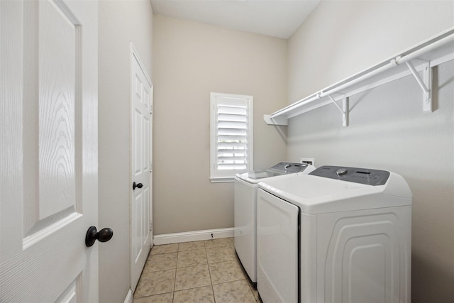 laundry room with laundry area, light tile patterned floors, washing machine and dryer, and baseboards