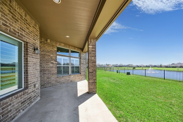 view of yard featuring a patio area, a fenced backyard, and a water view