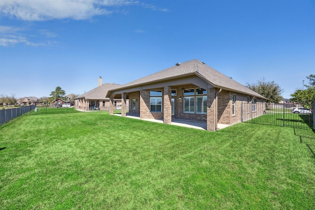 rear view of house featuring a lawn, brick siding, and a fenced backyard