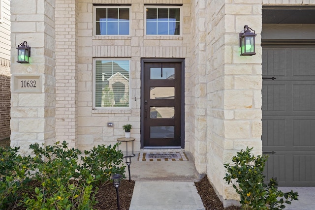 doorway to property featuring a garage and stone siding