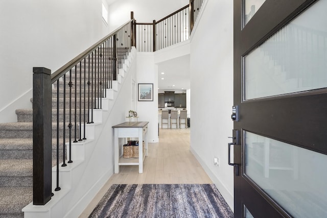 entrance foyer featuring stairway, baseboards, wood finished floors, and a towering ceiling