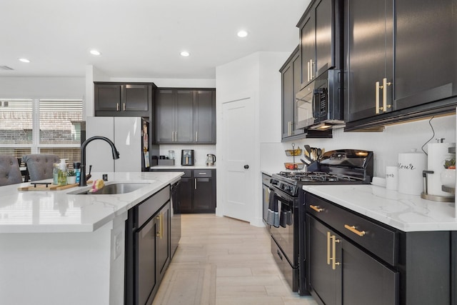 kitchen featuring a sink, light stone counters, recessed lighting, black appliances, and a kitchen island with sink