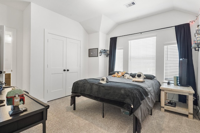 carpeted bedroom featuring a closet, visible vents, and vaulted ceiling